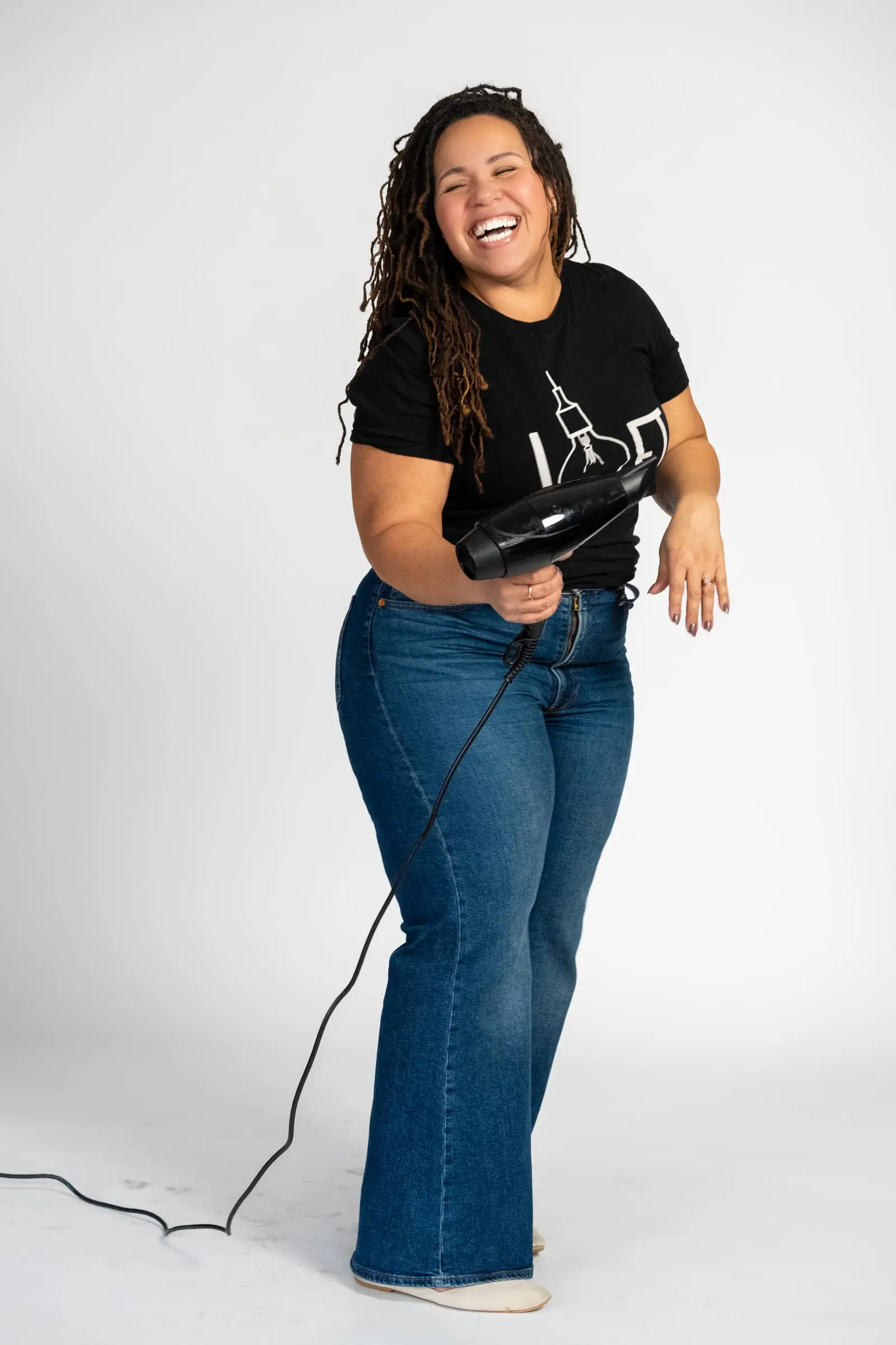 Loft stylist laughing with a blow dryer
